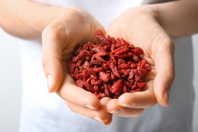 Photo of Woman holding red dried goji berries, closeup