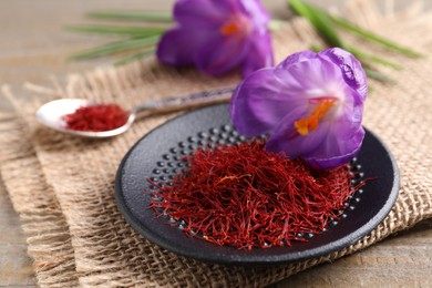 Photo of Dried saffron and crocus flowers on wooden table, closeup