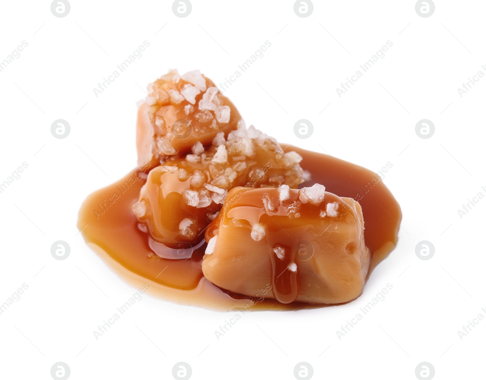 Photo of Yummy caramel candies and sea salt isolated on white