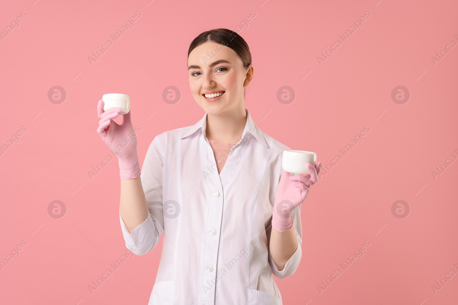 Photo of Cosmetologist with cosmetic products on pink background