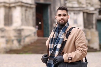 Photo of Smiling man in warm scarf outdoors. Space for text