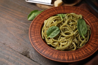 Tasty pasta with spinach on wooden table, space for text