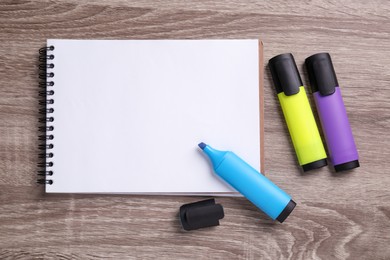 Photo of Empty notebook and markers on wooden table, flat lay