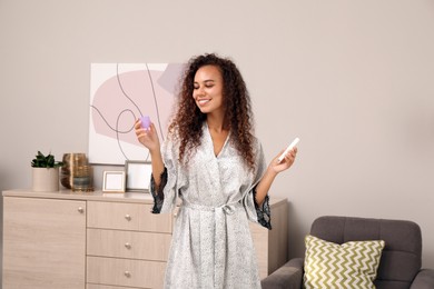 Photo of Young African American woman with menstrual cup and tampon at home