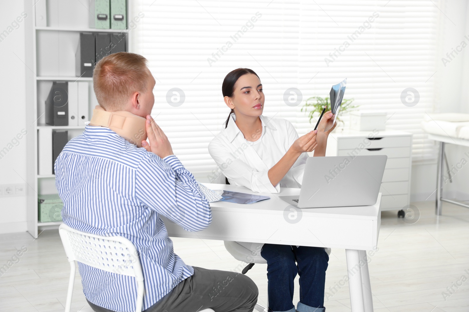 Photo of Doctor with neck MRI image consulting patient in clinic