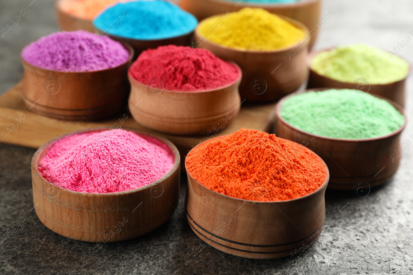 Photo of Colorful powder dyes on grey background, closeup. Holi festival