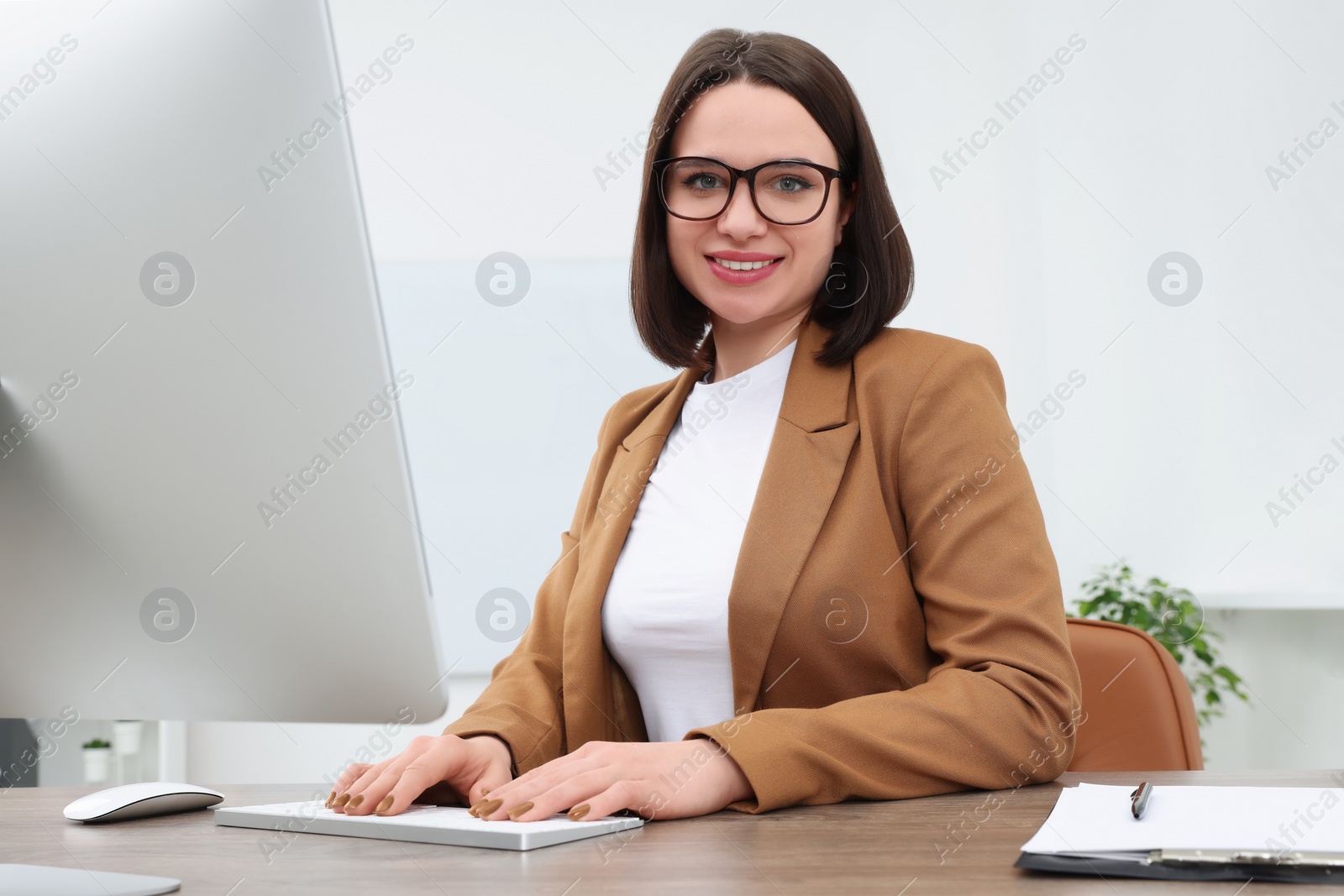 Photo of Happy young intern working at table in modern office