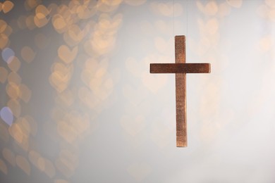 Photo of Wooden cross against blurred lights, closeup with space for text. Religion of Christianity