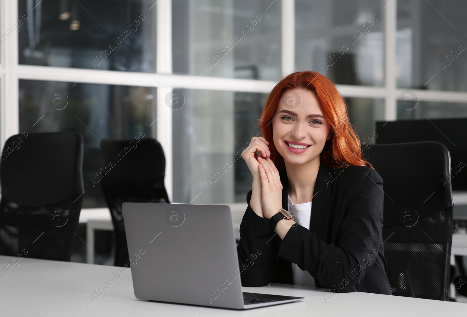 Photo of Happy woman working with laptop at white desk in office