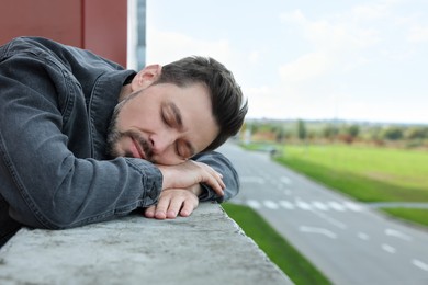 Photo of Tired man sleeping on stone surface outdoors. Space for text