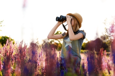 Teenage girl with binoculars in field. Summer camp