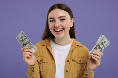 Happy woman with dollar banknotes on purple background