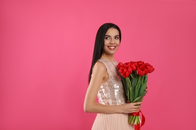 Happy woman with red tulip bouquet on pink background, space for text. 8th of March celebration