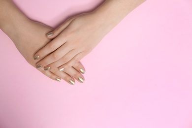 Photo of Woman showing golden manicure on color background, top view with space for text. Nail polish trends