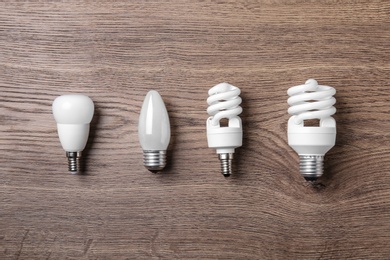 Photo of New fluorescent lamp bulbs on wooden background, flat lay