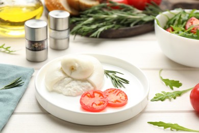 Photo of Delicious burrata cheese with rosemary and tomato on white wooden table