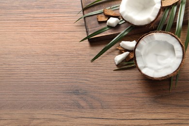 Photo of Ripe coconut with cream on wooden table, above view. Space for text