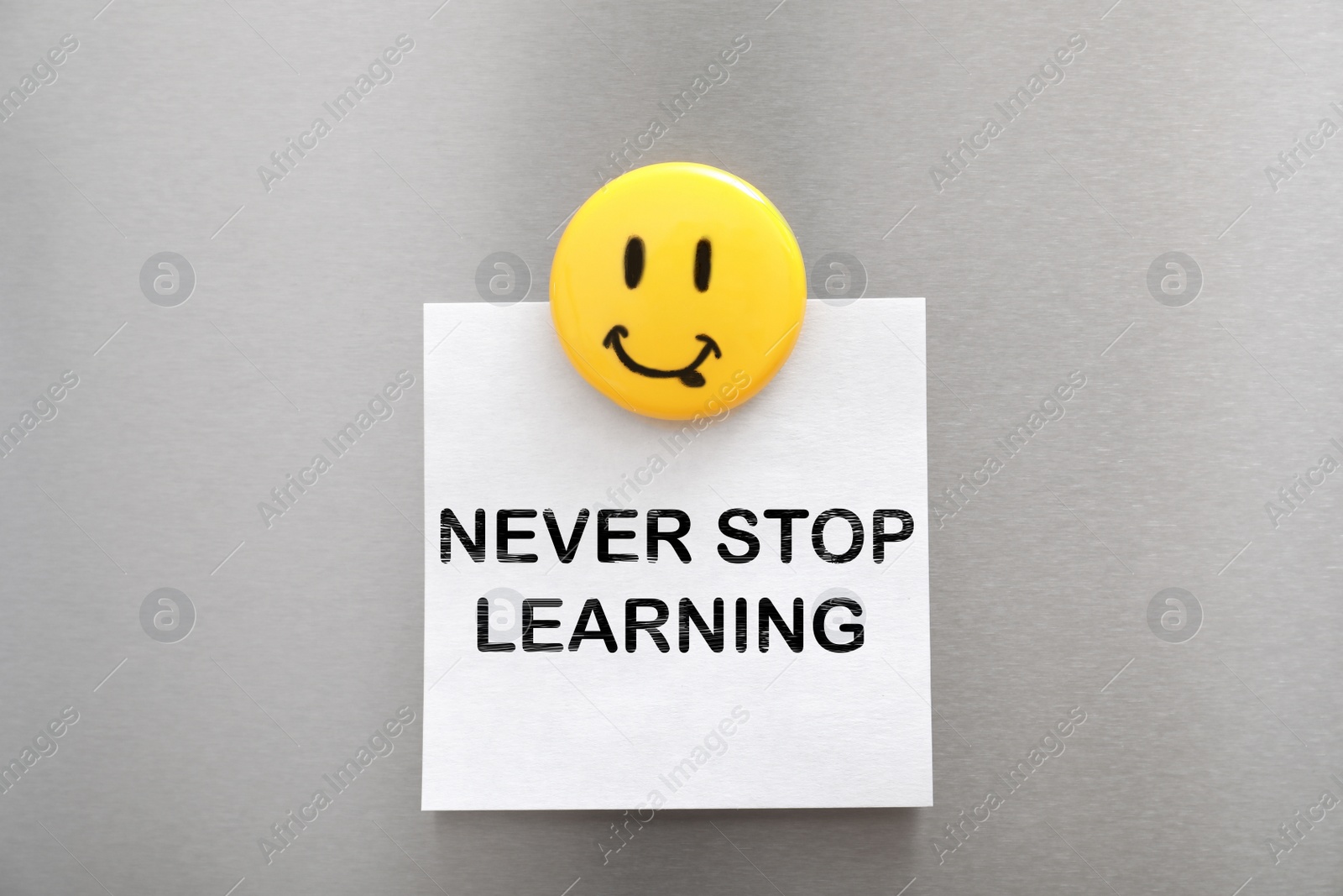 Image of Sheet of paper with phrase NEVER STOP LEARNING and magnet on refrigerator door