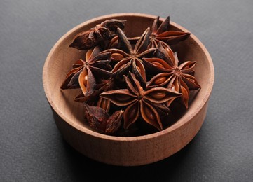 Photo of Aromatic anise stars in wooden bowl on grey background