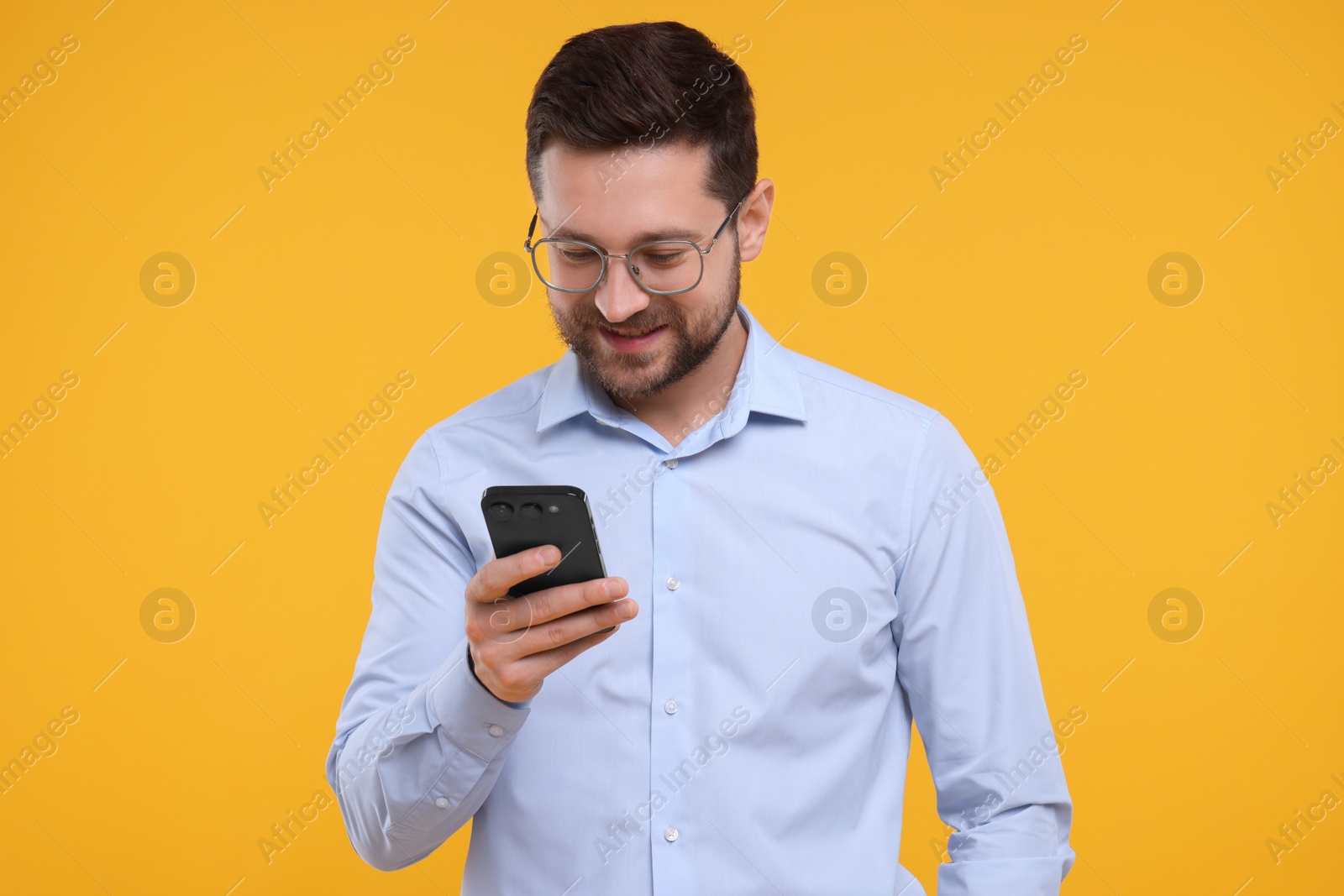 Photo of Happy man using smartphone on yellow background