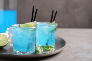 Photo of Tasty fresh light blue drink with lime on grey table, space for text