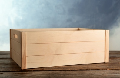 Wooden crate on table against color background