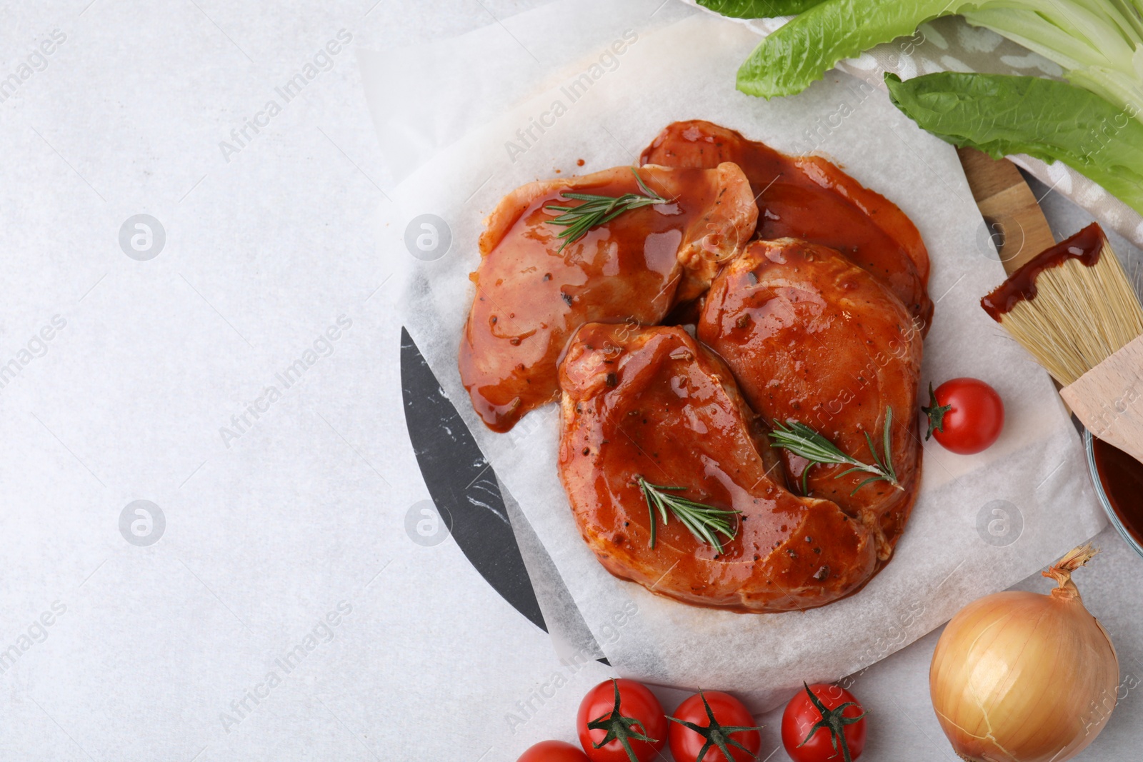 Photo of Flat lay composition with raw marinated meat, products and basting brush on light table. Space for text