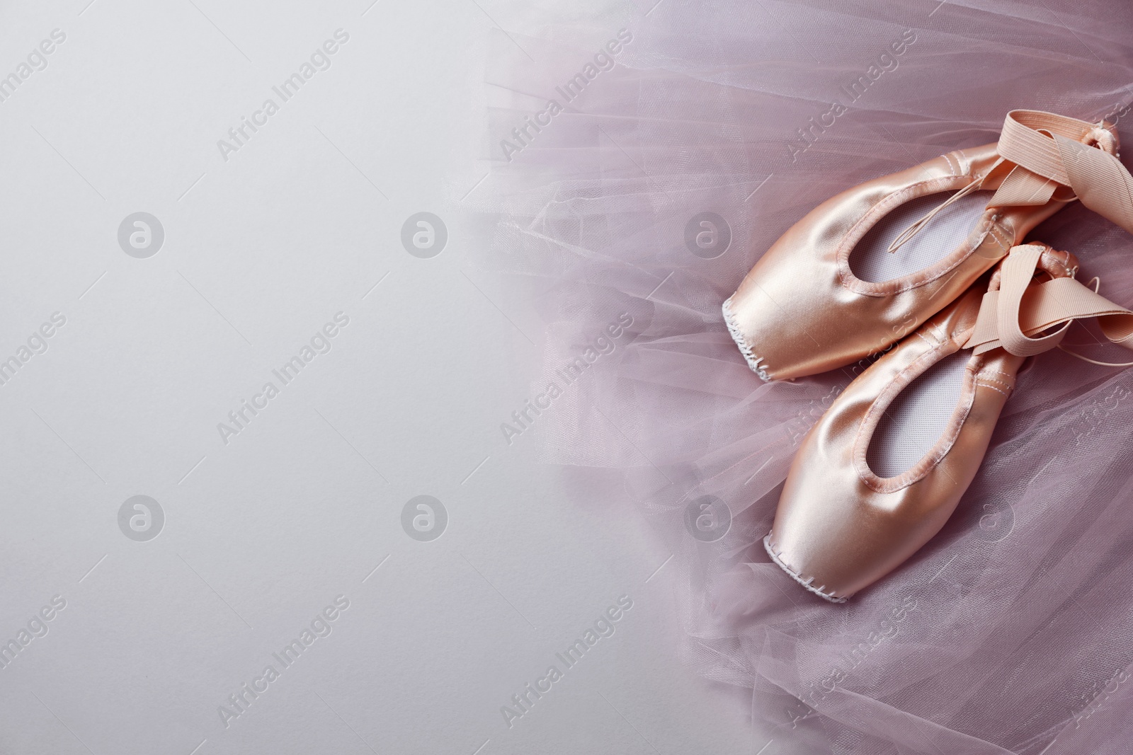 Photo of Ballet shoes. Elegant pointes and tutu on light grey background, top view. Space for text