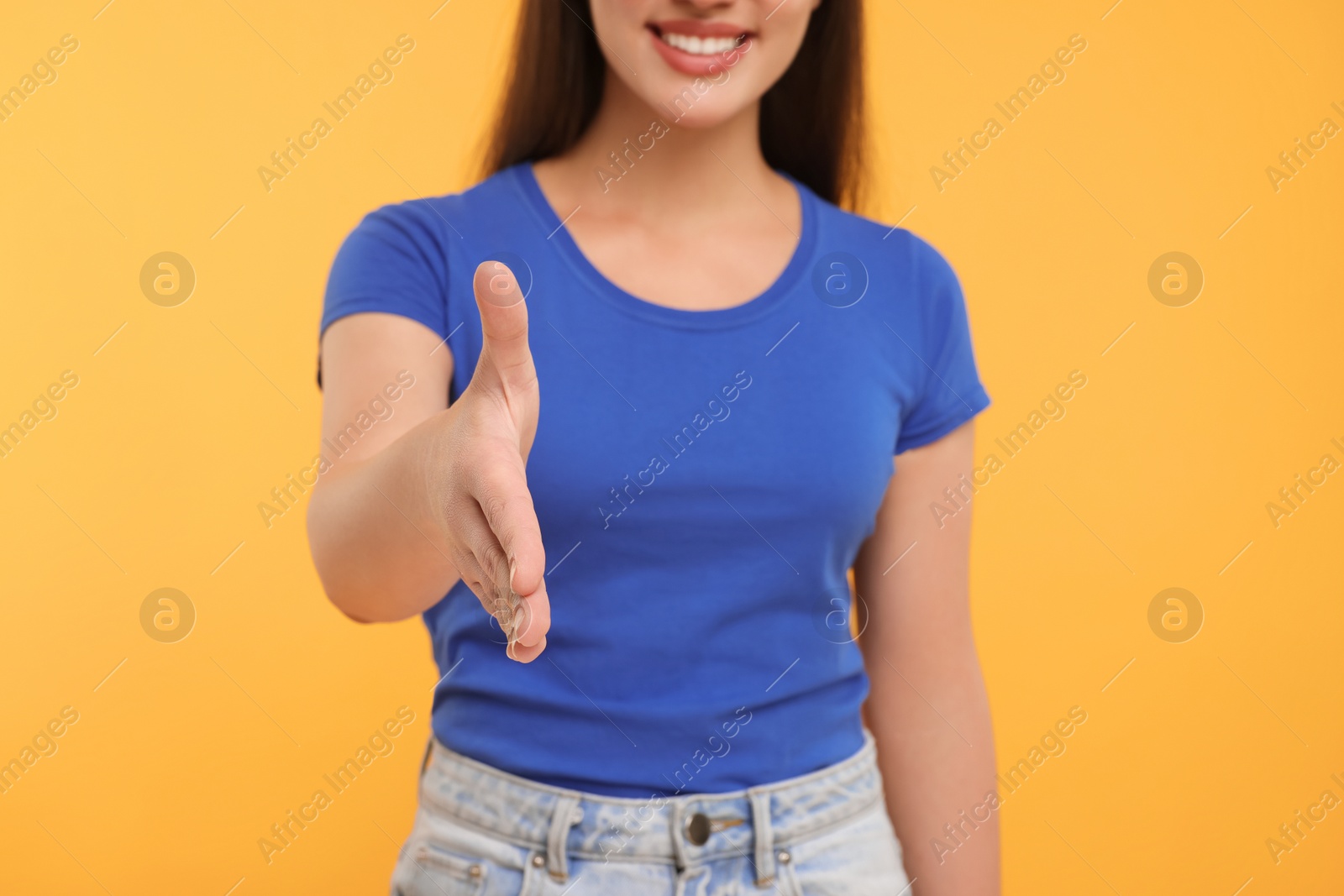 Photo of Woman welcoming and offering handshake on yellow background, closeup