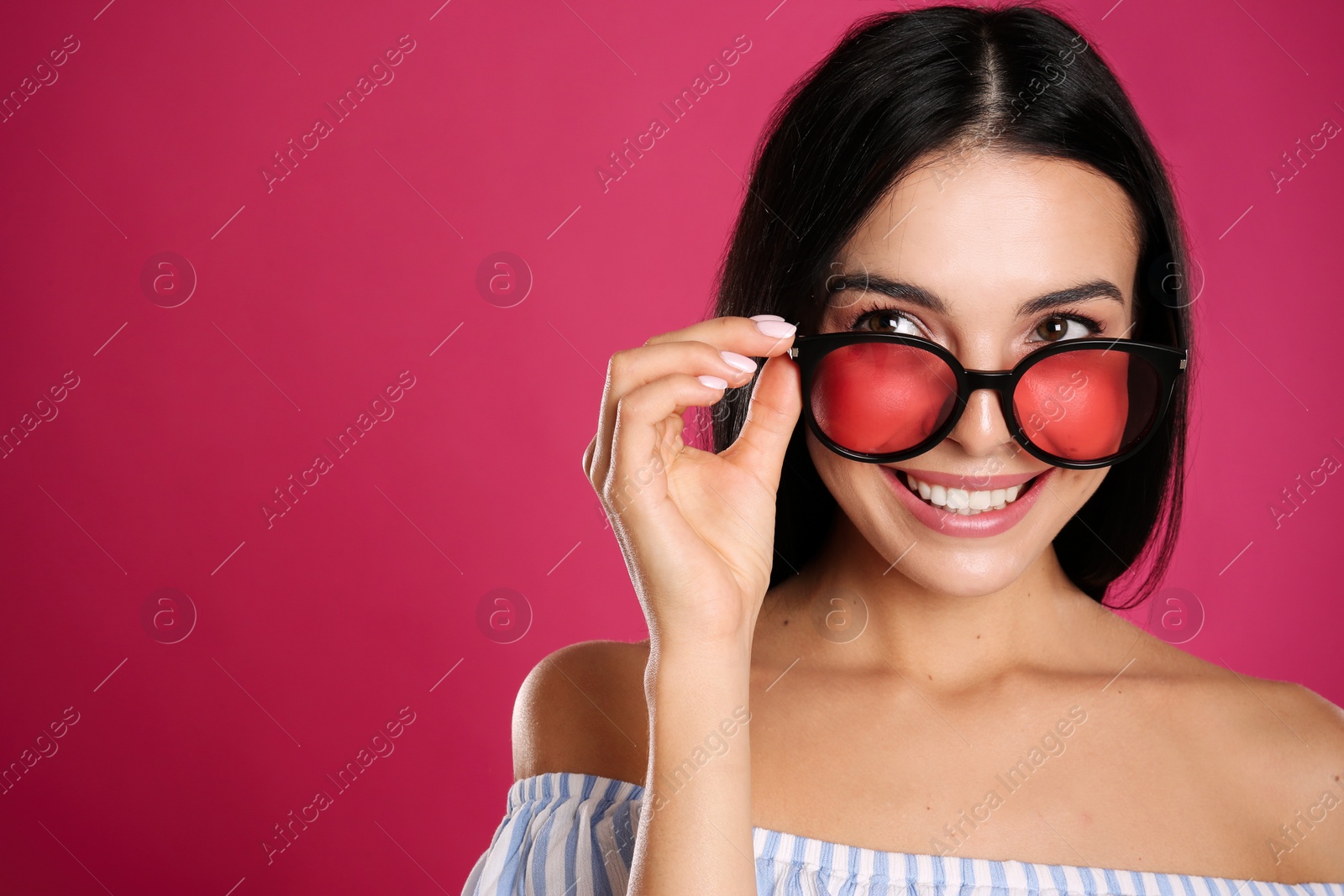 Photo of Beautiful woman wearing sunglasses on pink background, closeup. Space for text