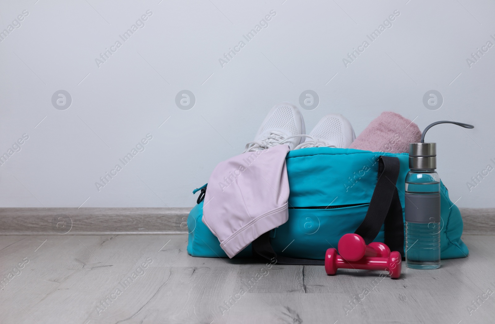 Photo of Stylish sports bag and different gym stuff on wooden floor indoors. Space for text