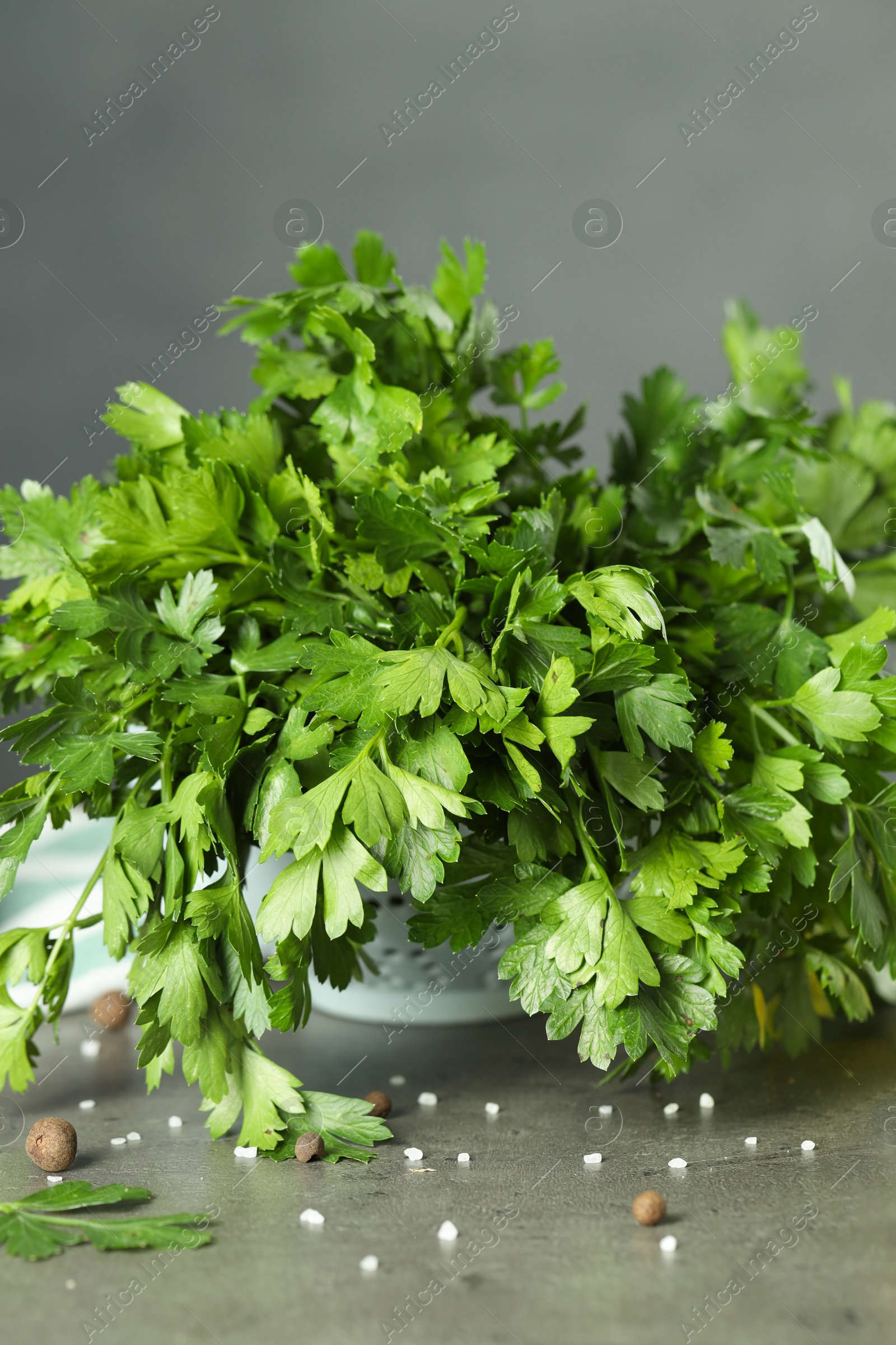 Photo of Fresh parsley, spices and other products on grey table, closeup