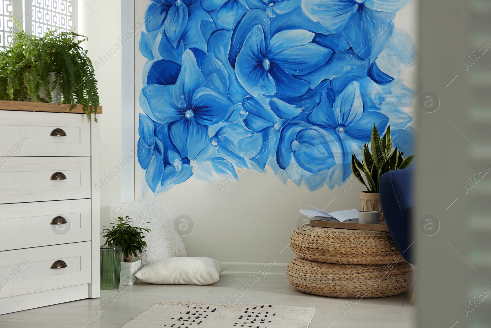 Photo of Stylish living room with blue flowers painted on wall. Floral pattern in interior design