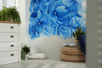 Stylish living room with blue flowers painted on wall. Floral pattern in interior design