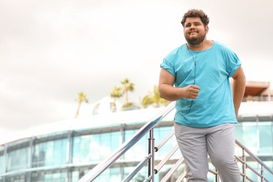 Photo of Young overweight man in sportswear outdoors. Fitness lifestyle