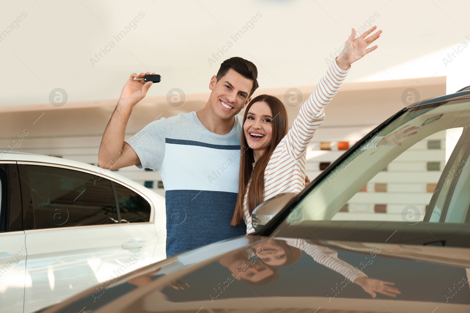 Photo of Happy couple with car key in modern auto dealership