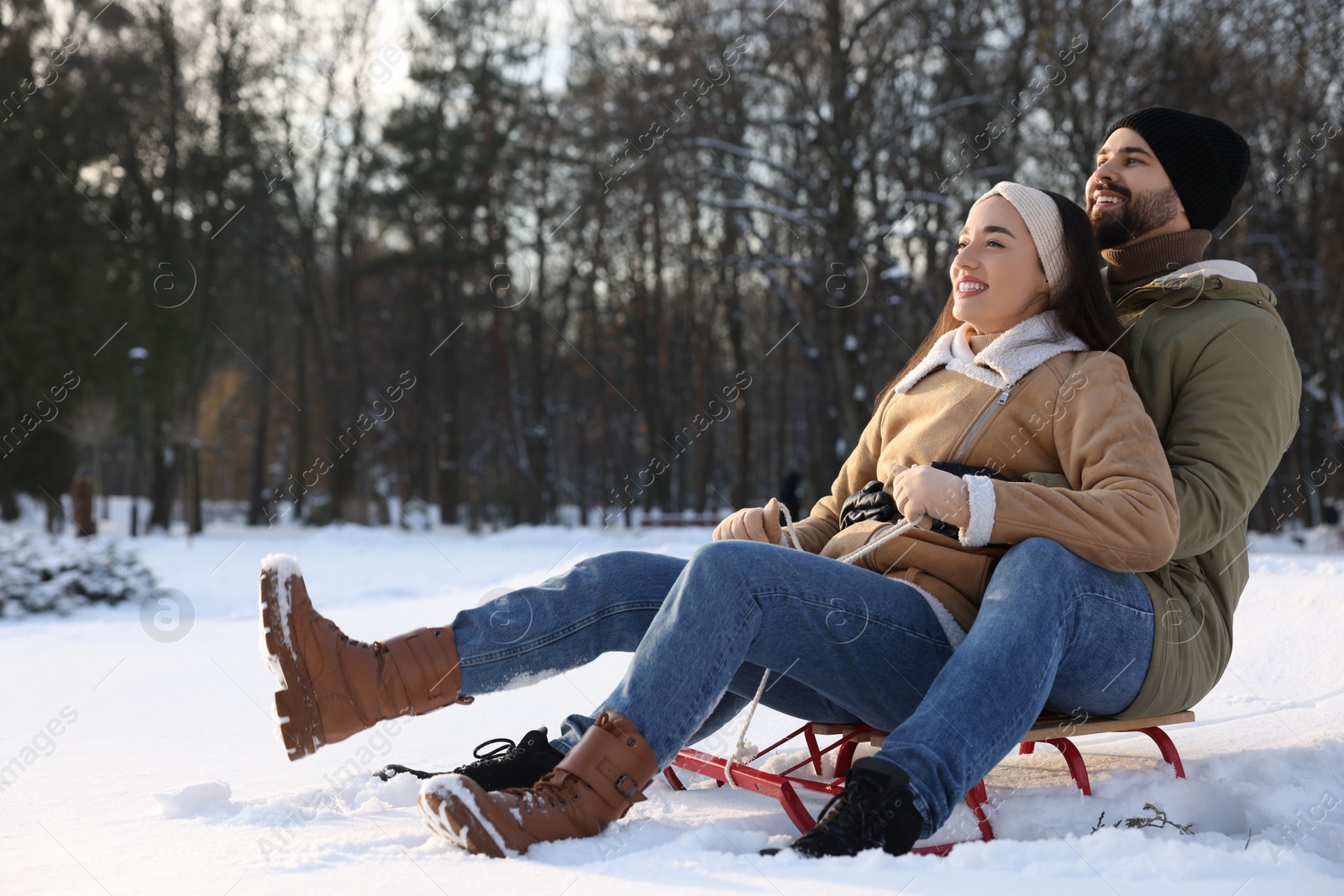 Photo of Happy young couple sledding outdoors on winter day