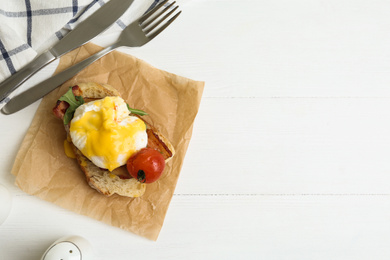 Photo of Delicious egg Benedict served on white wooden table, flat lay. Space for text