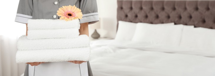 Image of Chambermaid with stack of fresh towels in hotel room, closeup view with space for text. Banner design