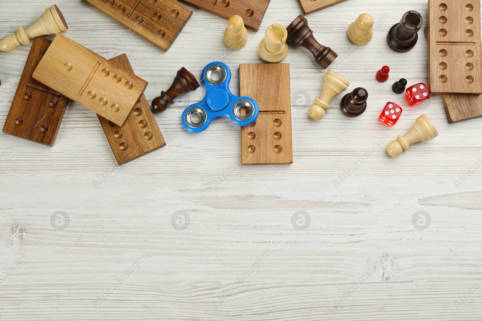 Photo of Elements of different board games on white wooden table, flat lay. Space for text