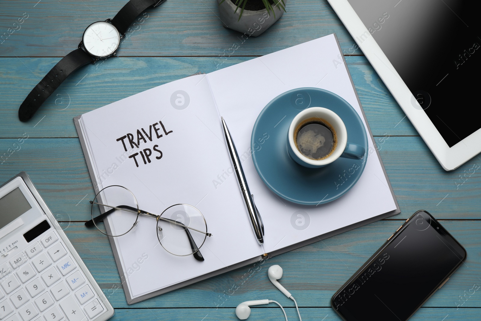 Photo of Notebook with phrase Travel Tips and office stationery on light blue wooden table, flat lay