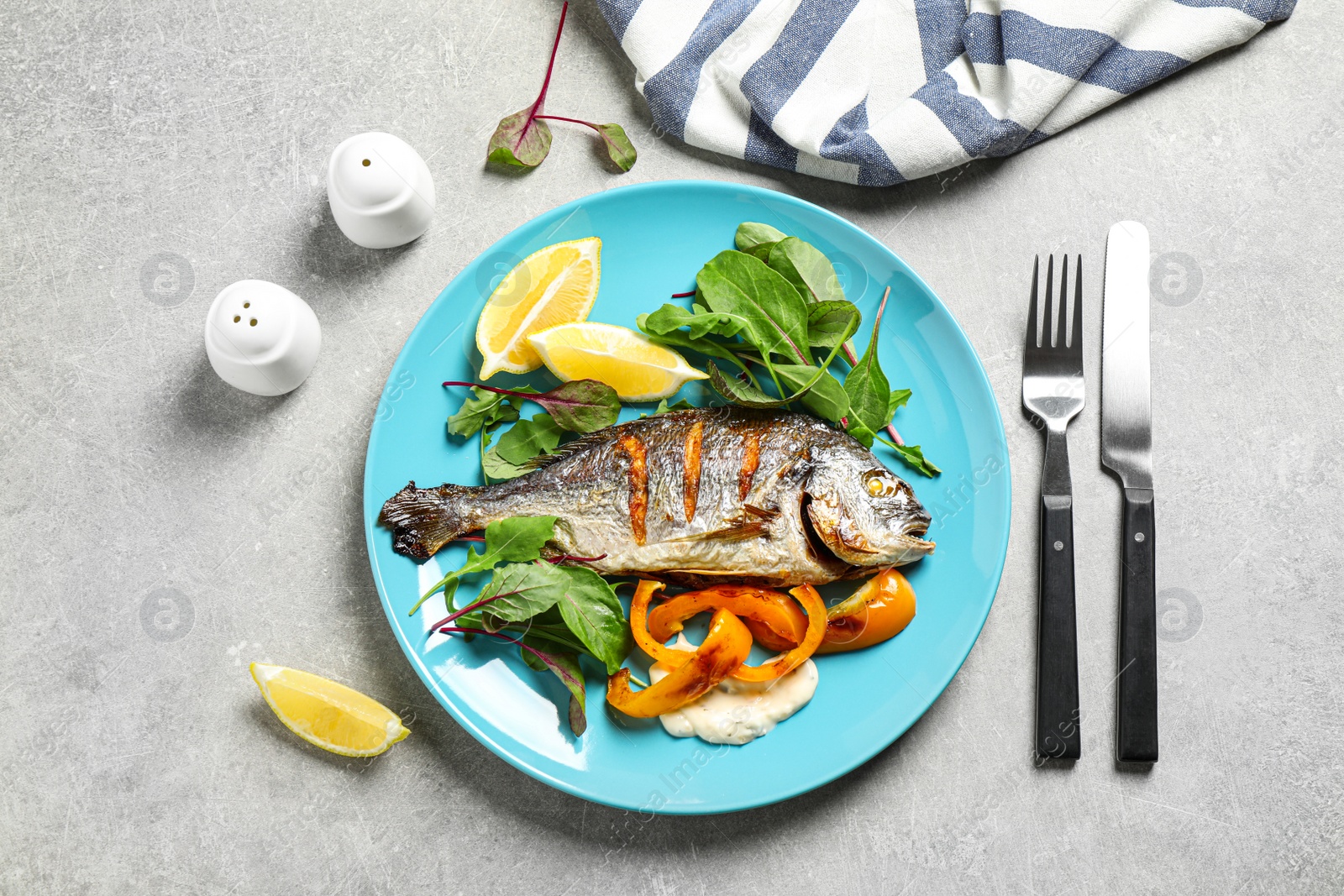 Photo of Delicious roasted fish with lemon on grey table, flat lay
