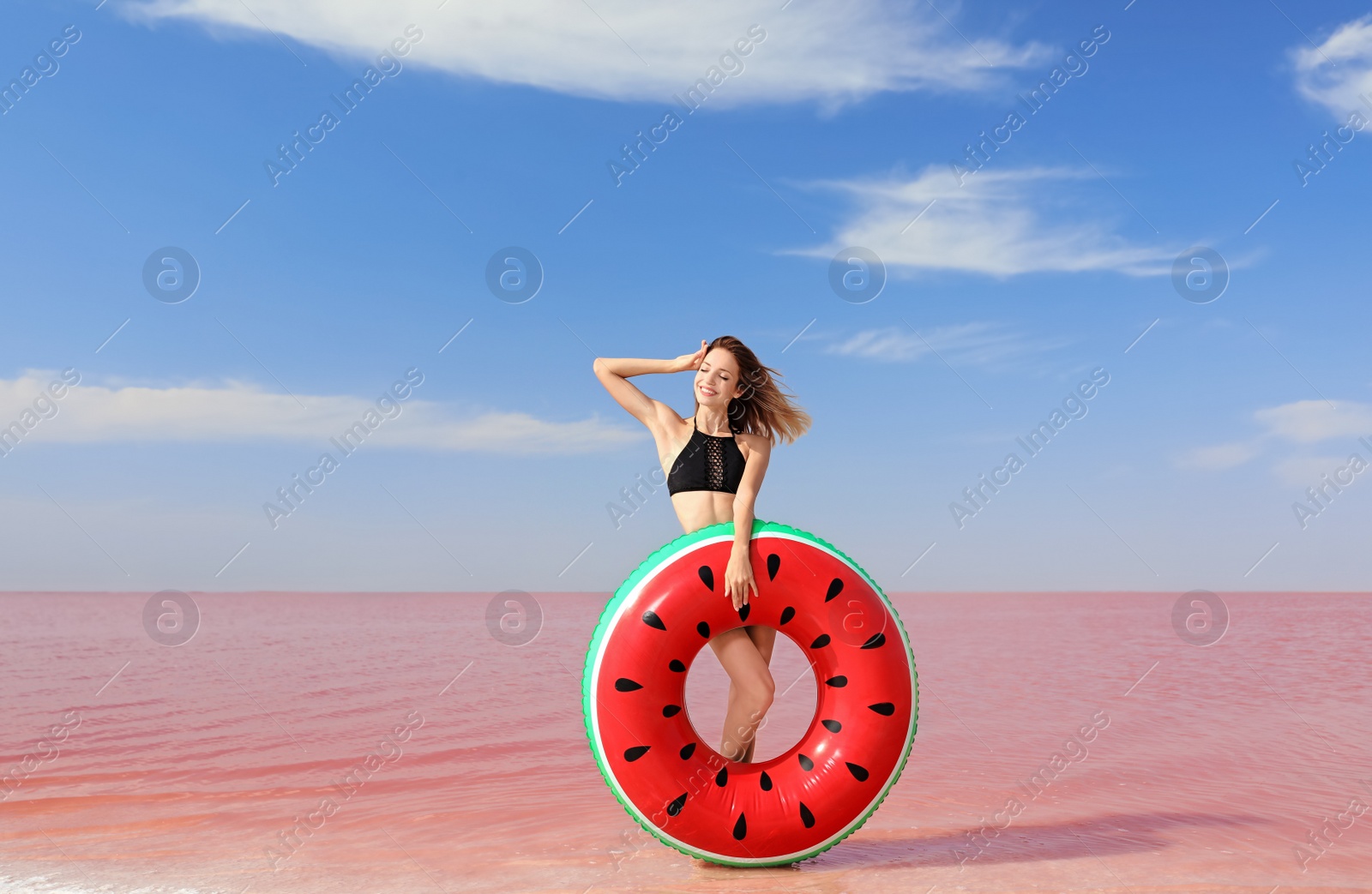 Photo of Beautiful woman with inflatable ring posing near pink lake on sunny day