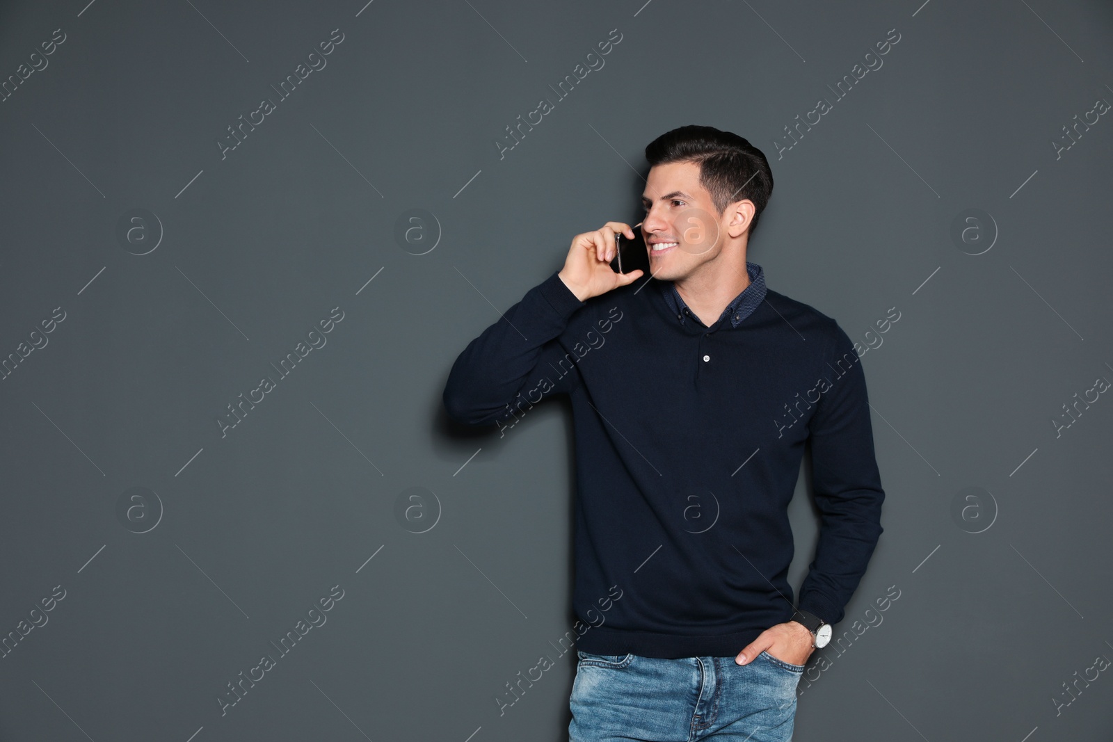 Photo of Portrait of handsome man talking on phone against grey background. Space for text