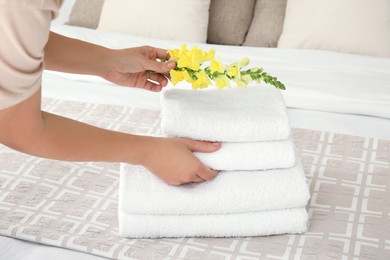 Photo of Woman putting flower on fresh towels in room, closeup