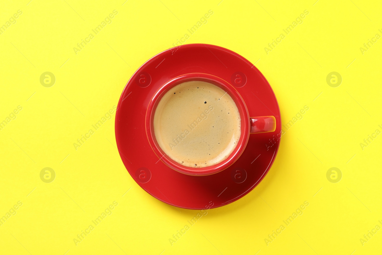 Photo of Tasty coffee in cup on yellow background, top view