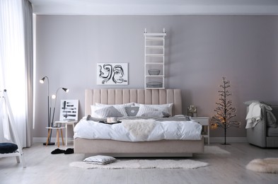 Photo of Cozy bedroom interior with decorative tree and beautiful pictures