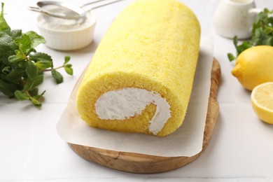 Photo of Delicious cake roll, lemons and mint on white table, closeup