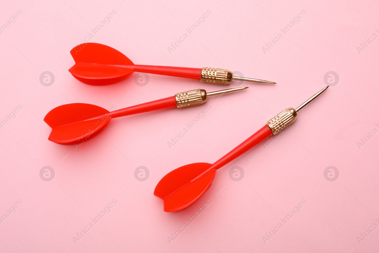 Photo of Red dart arrows on pink background, flat lay