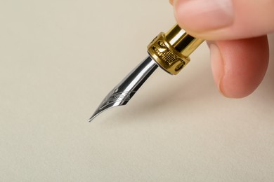 Photo of Woman with fountain pen above light paper, closeup. Space for text